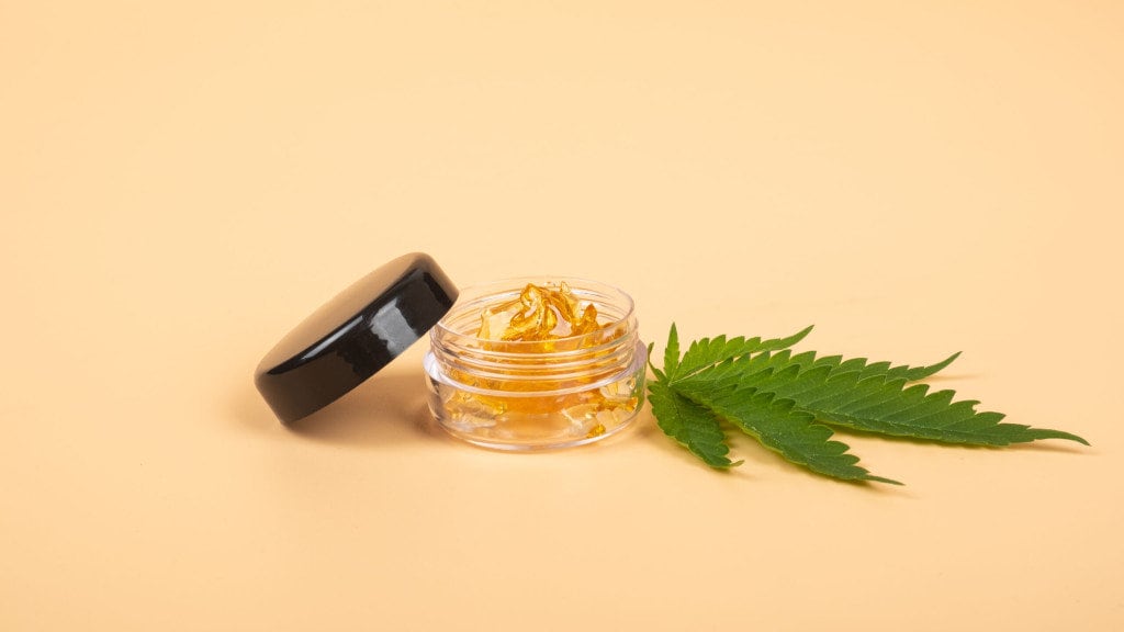 yellow cannabis oil wax resin and green leaf on yellow background
